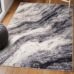 a white and black rug on top of a hard wood floor next to a chair