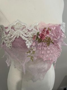 a white mannequin with pink flowers on it's side and lace around the waist