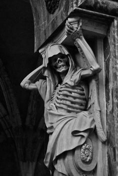 a black and white photo of a statue with a skeleton on it's head