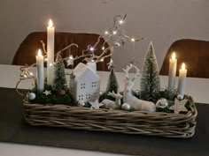 a wicker basket filled with christmas decorations and lit candles on top of a table