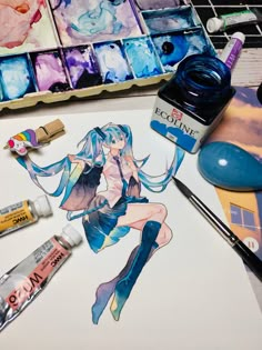 an artist's desk with some paint and supplies on it, including watercolors