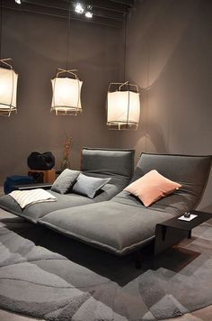 a large gray couch sitting on top of a rug next to two lamps and a table