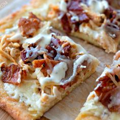 a pizza with bacon and cheese is cut into four pieces on a cutting board, ready to be eaten