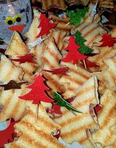 a plate full of cut up sandwiches with christmas trees on them and decorations around the edges