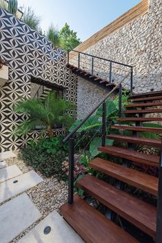 a set of wooden stairs next to a wall with geometric designs on it and trees in the background