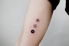 a woman's arm with three small flowers on the left side of her arm