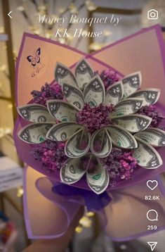 the money bouquet is made out of dollar bills and purple flowers with butterflies on it