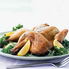 a whole chicken on a plate with lemons and parsley