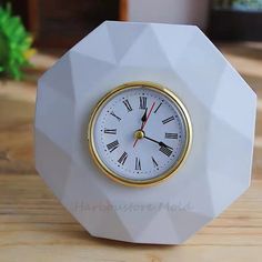 a white and gold clock sitting on top of a wooden table