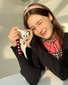 a woman taking a selfie with her camera in front of her face and wearing a pink headband