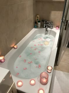 a bathtub filled with lots of candles next to a sink