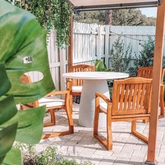 an outdoor table and chairs are set up under the pergolated area with green plants