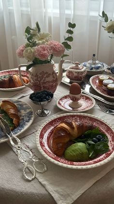 the table is set with croissants, pastries and flowers in vases