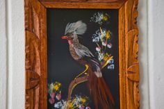 a painting on a wall with flowers and a bird sitting on it's back