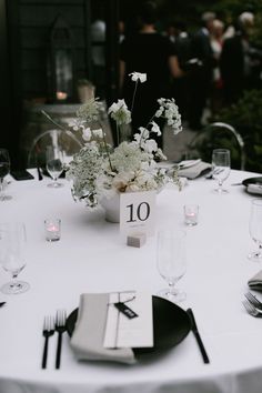 the table is set with white flowers and silverware