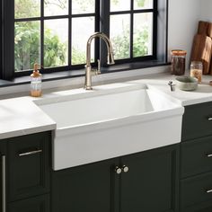 a kitchen sink sitting under a window in front of a counter top with utensils