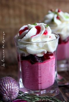 two desserts with whipped cream and cranberry sauce in small glass dishes on a table