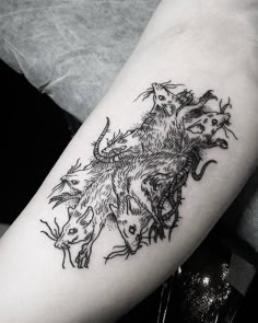 a black and white photo of a cat tattoo on the right arm, with three cats surrounding it