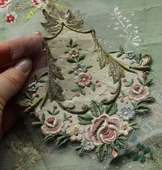 someone is stitching an embroidered fabric with flowers and leaves on the tablecloths