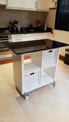 a kitchen island with black top and white baskets on wheels in front of the counter