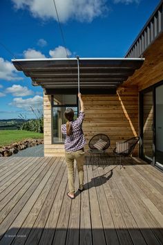 a woman standing on top of a wooden deck next to a building with a metal roof