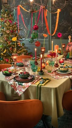 a dining room table set for christmas dinner with candles and ornaments hanging from the ceiling