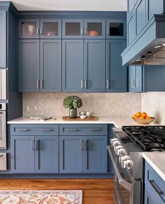 a kitchen with blue cabinets and white counter tops, silver appliances and a rug on the floor