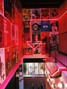 the inside of a restaurant with posters on the wall and stairs leading up to it