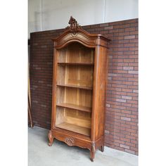 an old wooden bookcase next to a brick wall