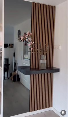 a vase with flowers is sitting on a shelf in front of a mirror that's reflecting the kitchen