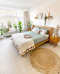 a bedroom with a bed, nightstands and potted plants