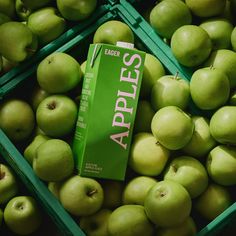 green apples are stacked up in crates with the box on top that says apple's