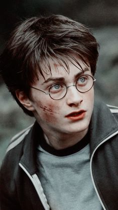 the young harry potter is wearing glasses and has blood on his face as he stares at something