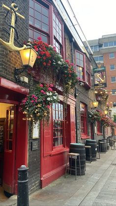 the outside of a restaurant with red doors and flowers hanging from it's windows