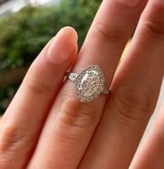 a woman's hand holding an engagement ring with a diamond in the center and side