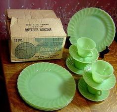 green plates and cups on a wooden table with a box in the backround