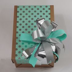 a green and silver gift box with polka dots on it's side, tied with a ribbon