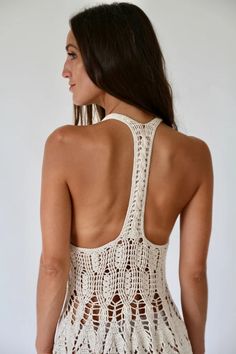 a woman wearing a white crochet swimsuit with her back to the camera