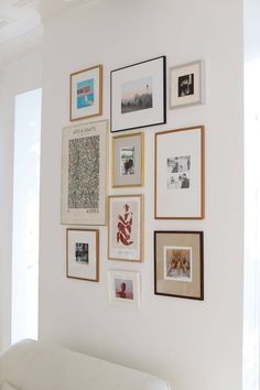 a white couch sitting in front of a wall filled with pictures and framed photos on it