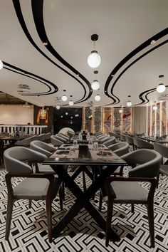 a dining room with black and white patterned flooring, chandeliers and chairs