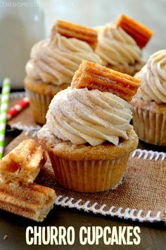 some cupcakes with icing and cinnamon sticks on a cloth next to them