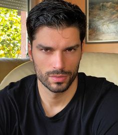 a close up of a person wearing a black shirt and looking at the camera with a serious look on his face