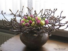 a vase filled with flowers sitting on top of a wooden table next to a window