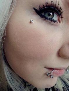 a woman with piercings on her nose and eyeliner is looking at the camera