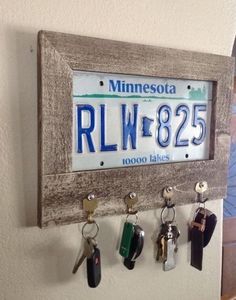 a license plate mounted to a wall with keys hanging from it's hooks,