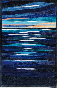 a quilted wall hanging with blue and orange stripes