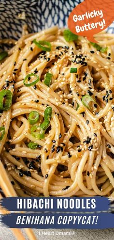 a plate of noodles with sesame seeds and green onions on top, next to chopsticks