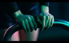 a person's hands on the handle of a metal pole in front of a dark background