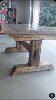 a wooden table sitting on top of a cement floor next to a store front window