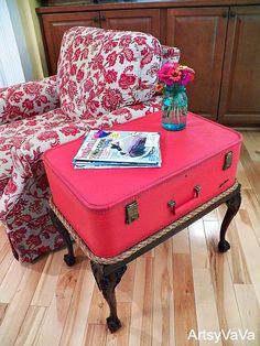 a pink suitcase sitting on top of a coffee table in front of a red couch